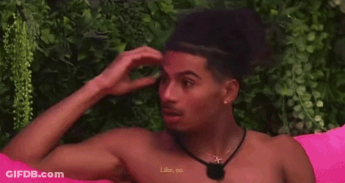 A Man Without A Shirt Is Sitting On A Pink Couch And Talking To Another Man . GIF