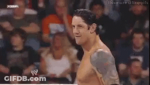 A Man Without A Shirt Is Smiling In Front Of A Crowd Of People . GIF