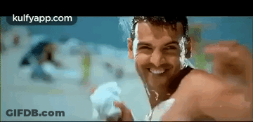 A Man Without A Shirt Is Smiling While Holding A Towel In His Hand . GIF