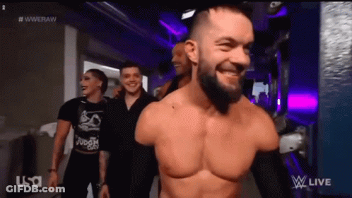 A Man Without A Shirt Is Smiling While Walking Down A Hallway With Other People . GIF