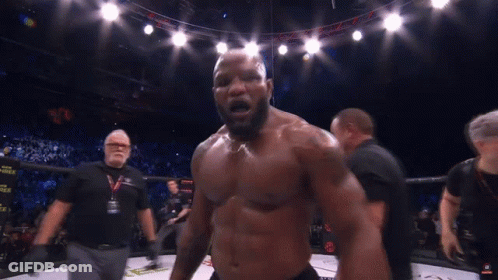 A Man Without A Shirt Is Standing In A Boxing Ring With A Referee Behind Him GIF