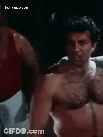 A Man Without A Shirt Is Standing In A Boxing Ring With His Hands Outstretched . GIF