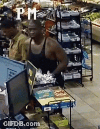A Man Without A Shirt Is Standing In A Grocery Store Behind A Counter . GIF