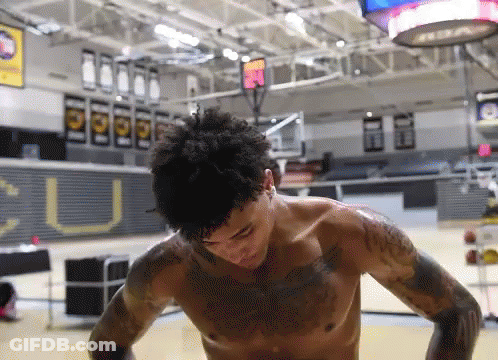 A Man Without A Shirt Is Standing In A Gym With A Sign That Says U On It GIF