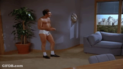 A Man Without A Shirt Is Standing In A Living Room GIF
