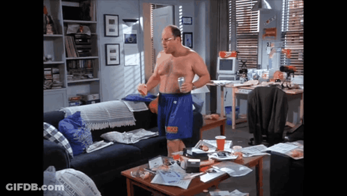 A Man Without A Shirt Is Standing In A Living Room With A Newspaper On The Coffee Table GIF