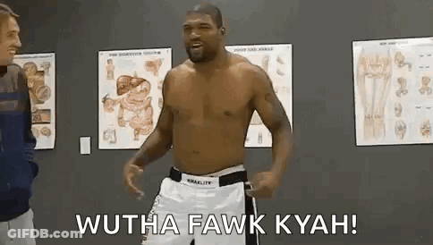 A Man Without A Shirt Is Standing In A Room With A Man Standing Next To Him . GIF