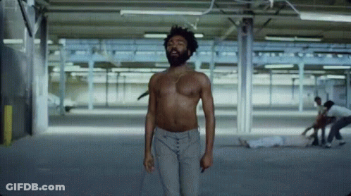 A Man Without A Shirt Is Standing In A Warehouse GIF