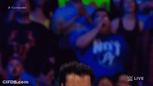 A Man Without A Shirt Is Standing In A Wrestling Ring With A Crowd Watching . GIF