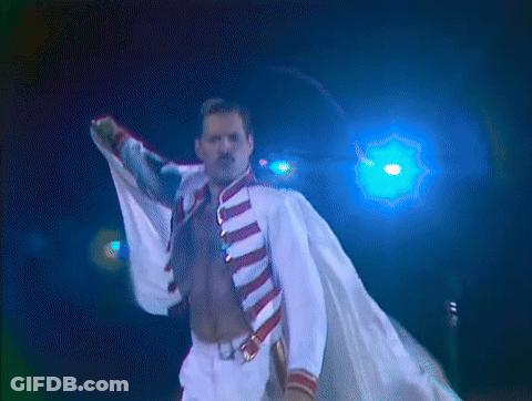 A Man Without A Shirt Is Standing In Front Of A Blue Light And Holding A Microphone GIF