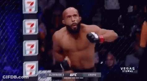 A Man Without A Shirt Is Standing In Front Of A Cage In A Ufc Fight . GIF