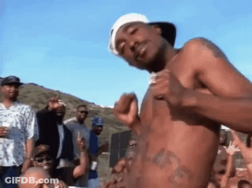 A Man Without A Shirt Is Standing In Front Of A Crowd . GIF