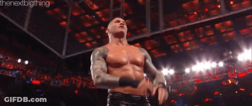 A Man Without A Shirt Is Standing In Front Of A Crowd In A Wrestling Ring . GIF