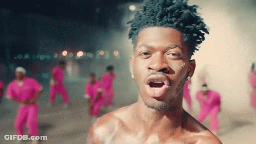 A Man Without A Shirt Is Standing In Front Of A Crowd Of People In Pink Pants GIF