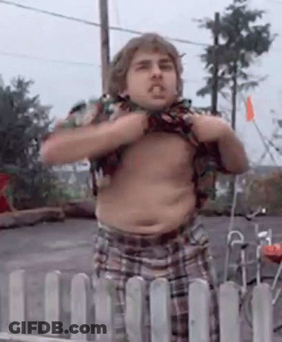 A Man Without A Shirt Is Standing In Front Of A Fence GIF