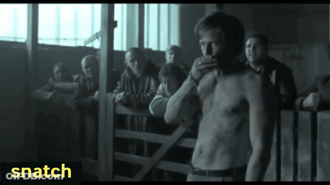 A Man Without A Shirt Is Standing In Front Of A Group Of People With Snatch Written On The Bottom Right GIF