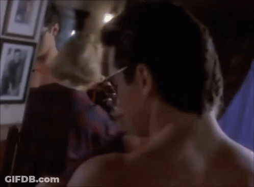 A Man Without A Shirt Is Standing In Front Of A Mirror Looking At His Reflection GIF