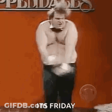 A Man Without A Shirt Is Standing In Front Of A Red Wall . GIF