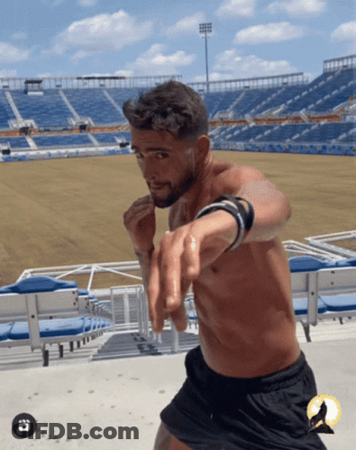 A Man Without A Shirt Is Standing In Front Of A Stadium That Says ' Florida ' On It GIF