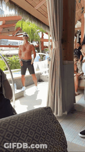 A Man Without A Shirt Is Standing In Front Of A Swimming Pool GIF