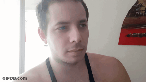 A Man Without A Shirt Is Standing In Front Of A Wall With A Picture Of Cars On It GIF