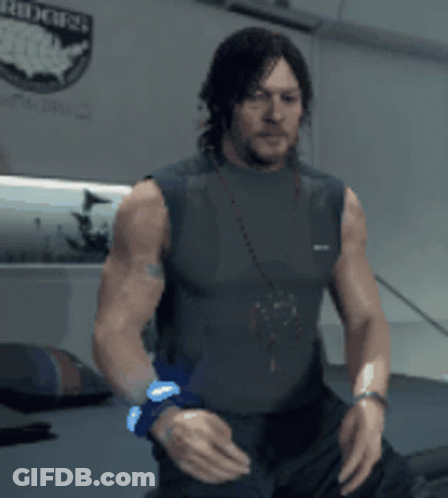 A Man Without A Shirt Is Standing In Front Of A Wall With A Sticker That Says Riders GIF