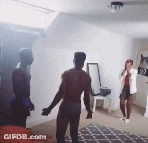 A Man Without A Shirt Is Standing In Front Of A Woman In A Room With A Sign That Says Go First GIF
