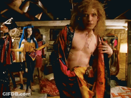 A Man Without A Shirt Is Standing In Front Of Mannequins In A Room GIF