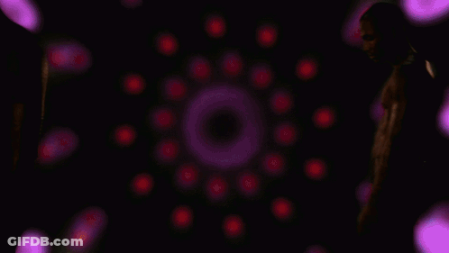 A Man Without A Shirt Is Standing In Front Of Purple Lights GIF