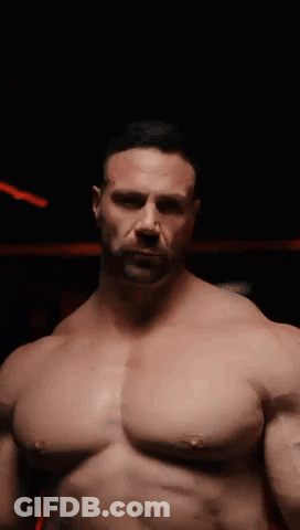 A Man Without A Shirt Is Standing In The Dark GIF