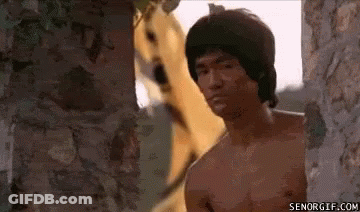 A Man Without A Shirt Is Standing Next To A Brick Wall With A Dog Behind Him . GIF