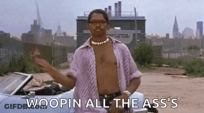 A Man Without A Shirt Is Standing Next To A Convertible Car In A Dirt Field . GIF