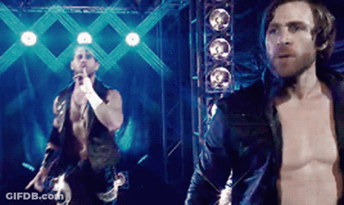 A Man Without A Shirt Is Standing Next To Another Shirtless Man On A Stage GIF