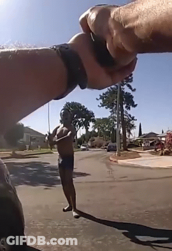 A Man Without A Shirt Is Standing On A Street Holding A Fishing Rod GIF