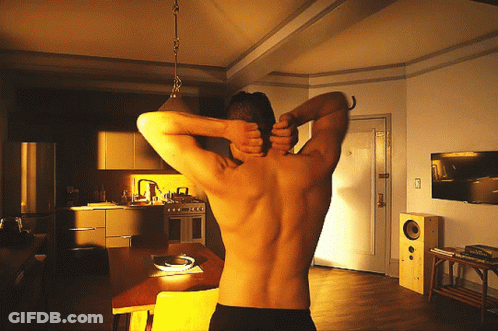A Man Without A Shirt Is Stretching His Back In A Kitchen GIF