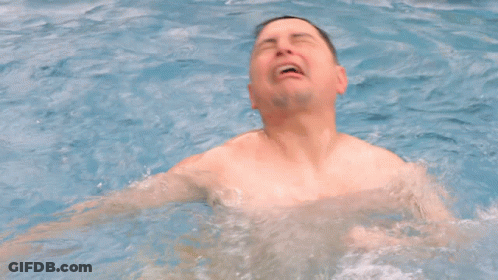 A Man Without A Shirt Is Swimming In A Pool With His Mouth Open GIF