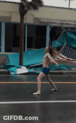 A Man Without A Shirt Is Walking Down A Street GIF