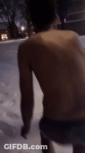 A Man Without A Shirt Is Walking In The Snow At Night GIF