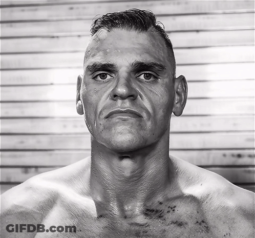 A Man Without A Shirt Looks At The Camera With A Serious Look On His Face GIF