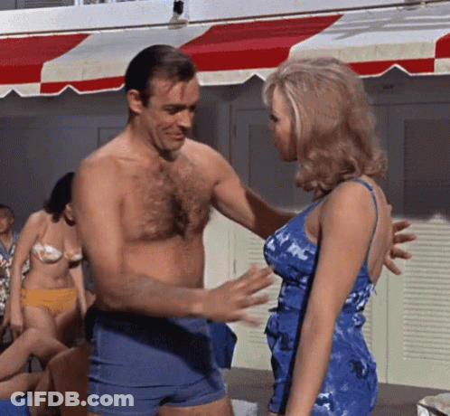 A Man Without A Shirt Talks To A Woman In A Blue Dress GIF