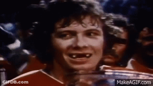 A Man Without Teeth Is Smiling While Holding A Trophy In Front Of A Crowd Of People . GIF