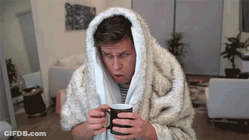 A Man Wrapped In A Furry Blanket Holds A Cup Of Coffee GIF