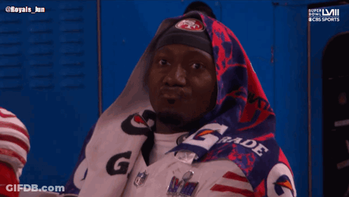 A Man Wrapped In A Gatorade Blanket Looks At Something GIF