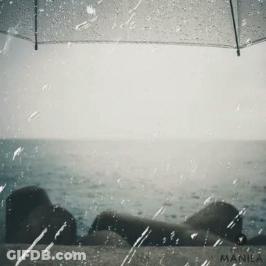 A Manila Photo Of A Person Under An Umbrella With The Ocean In The Background GIF