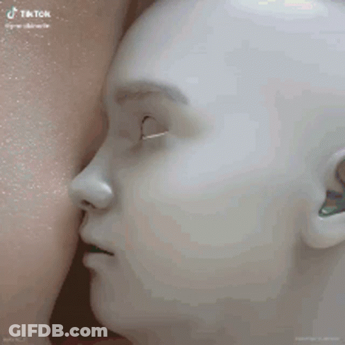 A Mannequin With Its Mouth Open Is Being Breastfed By A Woman . GIF