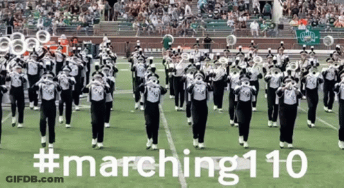 A Marching Band Performs On A Field With The Hashtag # Marching110 Written On The Bottom GIF
