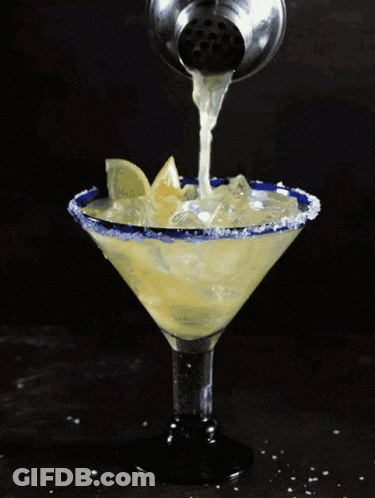 A Margarita Is Being Poured Into A Martini Glass With Ice GIF