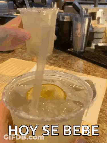 A Margarita Is Being Poured Into A Plastic Cup With A Straw And The Words Hoy Se Bebe On The Bottom GIF