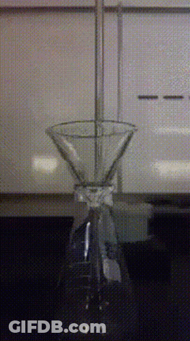 A Martini Glass Is Sitting On A Table In Front Of A White Cabinet GIF