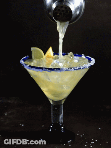 A Martini Is Being Poured Into A Martini Glass GIF